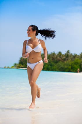 Sommerreisen als Sporturlaub. Frau beim Joggen am Strand